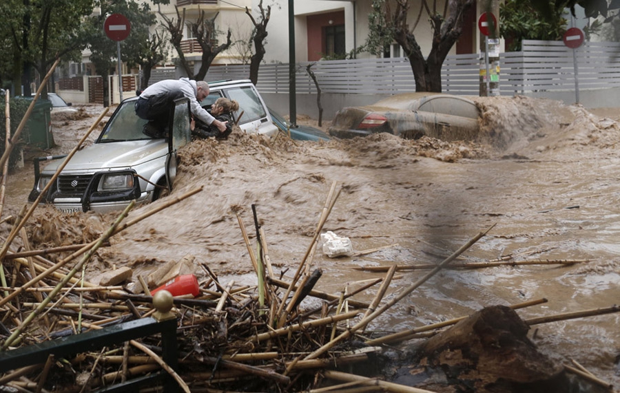 22 февраля, Афины, Греция. Мужчина помогает женщине вылезти из машины во время сильного, вызванного ливнями наводнения в районе Афин Халандри