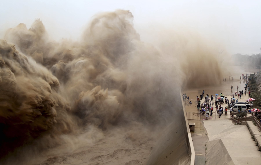 6 июля, Цзиюань, провинция Хэнань, Китай. Люди смотрят на волны в водохранилище Сяоланди на реке Хуанхэ во время ежегодной операции по очистке дна от скопившегося песка и ила