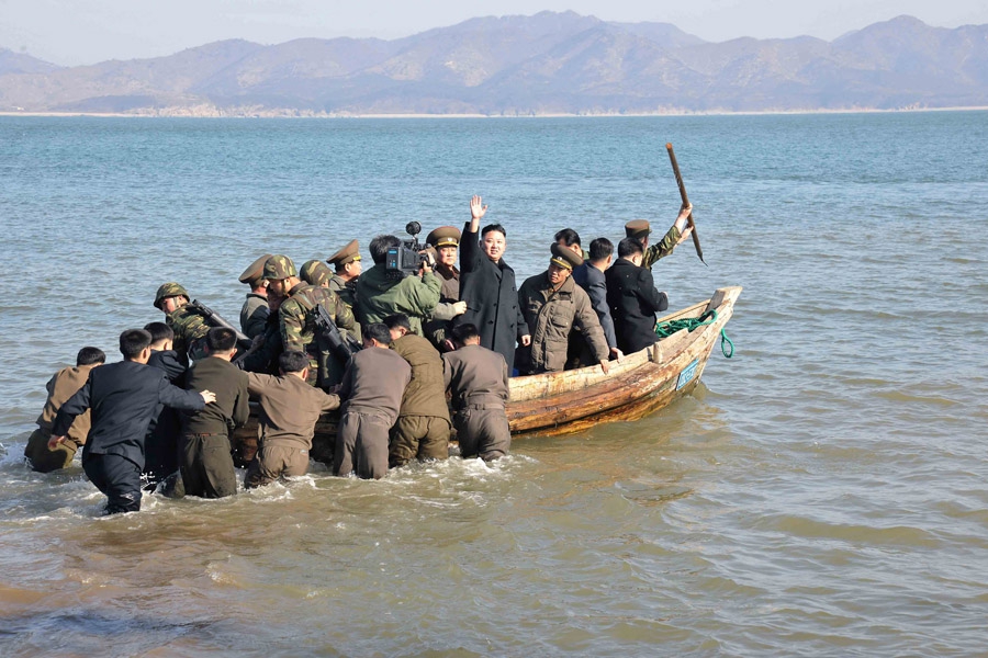 11 марта, Северная Корея. Северокорейский лидер Ким Чен Ын (в центре) машет рукой, стоя на лодке во время визита на военную базу на острове, находящемся недалеко от границы с Южной Кореей