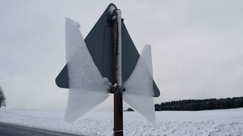  / Looking at the back side of the traffic sign you can understand what happened here. The snow had been sticking to the back of the traffic sign and before freezing it partially melted creating a thin ice layer. During the next day this ice had been melting while still sticking a little bit to the downside. And this way the angel spread its wings!