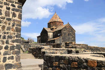 Древние стены и храмы в монастыре Севанаванк / Древние стены и храмы в монастыре Севанаванк в Армении: на фоне голубого неба в ясный майский день.