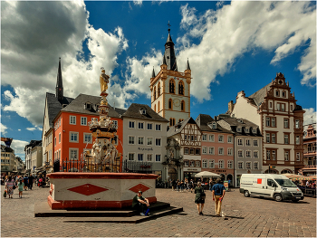 Рыночная площадь города Трир / По древней европейской традиции главной площадью в городе называют клочок земли, на котором и футбольное поле не уместилось бы. Трир не выделяется из общего ряда – Hauptmarkt (Рыночная площадь) представляет собой угол двух улиц с максимальным расстоянием между домами метров в 70.

Но согласно другой европейской традиции, даже на этих минимальных площадях горожане умудрялись разместить немало интересных достопримечательностей. В Трире это здания, выстроенные минимум в четырёх архитектурных стилях, а также Крест и Фонтан.
