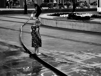 &nbsp; / Девочка играет с водой из шланга на городской улице