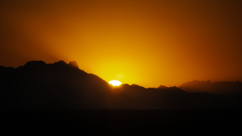 Закат солнца в пустыне / Закат солнца в пустыне - это впечатляющее зрелище нереального солнечного диска. опускающегося в раскаленный за день песок.
