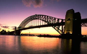 &nbsp; / The Harbour Bridge is as classic a symbol of Sydney as the shells of the Opera House itself.

Sydney Harbour Bridge, seen here at sunset, connects the Sydney central business district with the North Shore commercial and residential areas.

When completed, in 1932, the bridge Down Under was the widest bridge on the planet and the world's largest single-arch bridge; but was not the longest.

The single arch design was built from both ends (using cable supports) and joined in the middle.

Built to carry motor vehicles, trains, trams (until 1958), pedestrians and bicycles, the bridge's span of 1,650 feet allows unobstructed passage for ships in Sydney Harbour.

https://travelnotes.org/pics/Australia/05-Sydney_Harbour_Bridge.htm