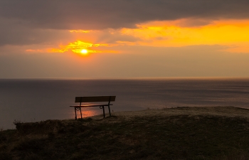В закате дня ,когда устало Солнце / В закате дня, когда устало солнце 
Расплескало огонь в ладонях туч, 
Тихо гаснет его последнее оконце, 
И рассветы уходят, как преданный пауч. 

Небо, выцветшее в акварели печали, 
Облака, словно письма, что время сожгло, 
И волна, прикоснувшись к песчаной устали, 
Унесла позолоту на самое дно. 

Тени длинные — кисти, что красят равнины, 
И ветра замерцавший, прохладный декольт… 
Это день, опуская ресницы-холмины, 
Дарит звёздам свой шёпот, свой тихий полёт. 

Лишь червонный отблеск на гребне волны 
Напоминает, что пламя не спит за горой, 
Что усталость — не кончик земной круговерти, 
А начало покоя, где ночь и прибой.
