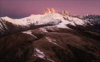 УШБА / Ушба (უშბა) - самая знаменитая гора в Сванетии и, наверное, одна из самых знаменитых на всем Кавказе, не считая Эльбруса. Она далеко не самая высокая (4690 метров), но отличается некоторой остроконечностью формы, и сложностью восхождения. 
По некоторым параметрам Ушба напоминает альпийский Маттерхорн (Монте-Червино). Тот имеет похожую форму, сравнимую высоту (4778) и примерно такую же категорию сложности. 
В Европе Ушбу называли &quot;Кавказским Маттерхорном&quot;. 
Ни одна из вершин Кавказа не овеяна таким ореолом легенд, историй и драматических фактов как Ушба. 
Для сванов Ушба - гора особенная. Любой мужчина этой крошечной горной страны вырастает с глубоким чувством уважения и трепета перед своим самым достойным личным испытанием – Ушбой. В самом облике этой горы заложен вызов мужеству человека. 
Грузия, Верхняя Сванетия, ноябрь 2025г. © https://phototravel.pro