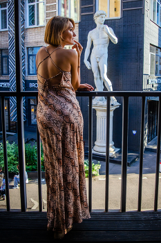 Евгения. Так ты Давид, да? / Девушка стоит на балконе, на фоне статуи Давида.