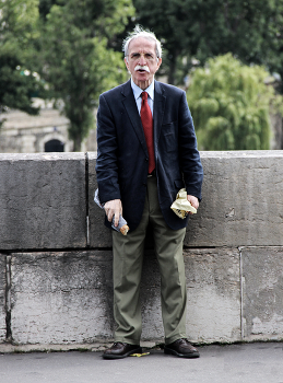 Парижанин / Житель Парижа, перекусывающий багетом на набережной Сены близ собора Парижской Богоматери 26 июня 2013 года.