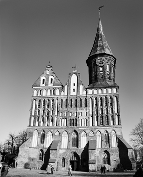 Кафедральный собор в оттенках черно-белого / Кафедральный собор в Калининграде — выдающийся памятник северной готической архитектуры XIV в., ставший настоящим культурным и философским символом города.Бывший храм отличается классическими для Средневековья архитектурными решениями. Его изюминка — ассиметричный, строгий и выразительный двухбашенный фасад. По горизонтали он визуально разделен штукатурными поясами, а по вертикали — арочными стрельчатыми проемами разных размеров.

Северная башня завершается треугольным фронтоном, а круглую южную венчает шпиль, на котором установлен флюгер. Фасад ее украшен часами-курантами — точной копией тех, что были установлены тут в XVII в, но до наших дней не дожили. Промежуток между башнями заполняет ажурный щипец. Внутри собора — восстановленные элементы сводов с росписями, витражи и трибуны для органа. Парадный вход украшает готическая арка.