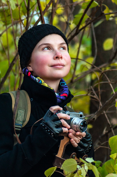 Лина. / Девушка с фотоаппаратом на фоне листвы деревьев.