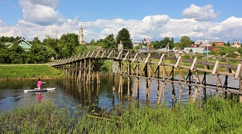 Символ стойкости / Мост, ведущий к церкви Богоявления на улице Шмидта в Суздале, был и остается символом стойкости и постоянного обновления. 
Он не раз подвергался испытаниям: горел, гнил, разрушался и смывался водой во время половодья. Но каждый раз, когда стихия отступала, жители города, как искусные мастера, восстанавливали его, возвращая к жизни. Эти временные мосты, называемые лавами, стали частью истории города, напоминая о неустанном стремлении людей к созиданию и преодолению трудностей.