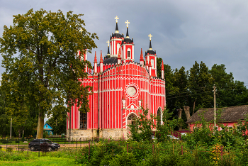 Жемчужина села Красное... / В 20 верстах к северо-западу от старинного городка Старица, что на юго-западе Тверской губернии, расположено сельцо Красное – бывшая вотчина дворян Полторацких. Некогда роскошный приусадебный ландшафтный парк с прудом давно зарос, а от каменного барского дома, который сгорел в лихих 1990-ых, остались руины. И только в помпезной архитектуре уцелевшего Преображенского храма торжествует славный дух былой эпохи.
Посреди нынешней запущенной постсоветской пасторали изящная церковь праздничного розового цвета, выполненная в псевдоготическом стиле, выглядит настоящей фантасмагорией. Сооружение имеет одну главу, которую обрамляют четыре башни и 16 белых каменных фигурных столбов.
Построено это чудо в конце XVIII века, когда усадьбой владел статский советник Марк Фёдорович Полторацкий. Необычная архитектура неслучайно повторяет формы известного Чесменского храма в Санкт-Петербурге, возведённого по приказу императрицы Екатерины II в честь победы русского флота над турками в бою при Чесме.
В строительстве церкви в селе Красном использовались те же проекты известного зодчего Юрия Фельтена, по которым создано питерское творение, но сам мастер в работах под Старицей не участвовал.
