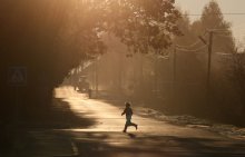 мальчик / мальчик перебигает дорогу в лучах утреннего солнца