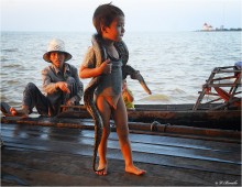 Жизнь на воде / Камбоджа. Озеро Тонлесап. Здесь люди (главным образом мигранты-вьетнамцы) живут на воде - в домах на сваях. В озеро, кишащее рыбой, змеями и крокодилами, сбрасывают отходы, из него же пьют, тут же купаются. Занимаются либо выращиванием риса (за 5 долларов в день), либо побирательством среди туристов, демонстрируя им земноводных, как на снимке, или просто прося подачку в бакс-другой.