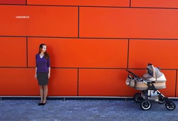 Мама и малыш в коляске / на фоне оранжевого фасада