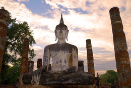 История религии / Древняя скульптура сидящего Будды крупным планом на закате. Исторический парк города Сукхотай, Таиланд