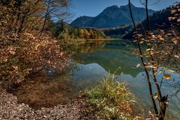 На берегу Schwanensee (Германия, Бавария) / Озеро Шванзее – это одно из озер, окружающих знаменитые баварские замки Хоэншвангау и Нойшванштайн. Шванзее самое маленькое из них по площади, но самое знаменитое. Именно оно подарило свое название знаменитому балету П.И.Чайковского «Лебединое озеро». Петр Ильич посетил эти места в 1876 году. В Москве ему был заказан романтический балет на симфоническую музыку. Чайковский вспомнил об опере Рихарда Вагнера &quot;Лоэнгрин&quot;, написанной на сюжет о Рыцаре Лебедя. За вдохновением композитор отправился в Баварию. Тем более что и до России уже дошла молва о загадочном баварском монархе Людвиге II, столь увлеченном этим сюжетом. Красота озера, необыкновенные пейзажи, сказочные замки – все это настолько вдохновило композитора, что была создана удивительная музыка, и родился знаменитый балет.