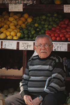 Арабский продавец в Бруклине / Продавец присматривает за выставленными на уличных лотках фруктами и овощами.