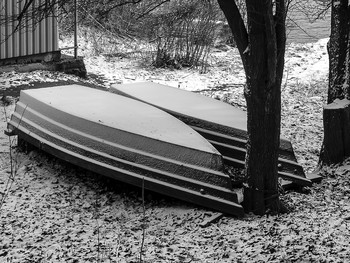 Зимний сезон / Перевернутые лодки присыпанные свежим снегом на берегу у воды в феврале