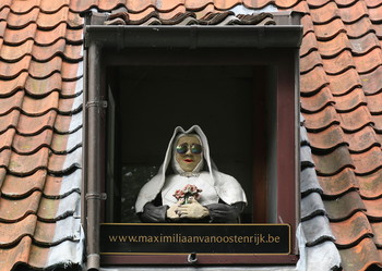 Скульптура монашки в Брюгге. / Окно крыши ресторана Maximiliaan фургона Oostenrijk Красная крыша, голубое небо.В Брюгге.