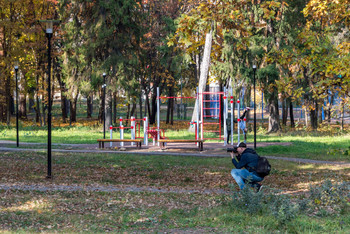 Фотография фотосессии фотографа. / Работа фотографа на природе в городском парке.