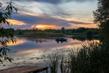 Вечер июня / Фотография маленькой реки на закате и рыбацкой лодки . Рыбаки спешат до хаты с уловом