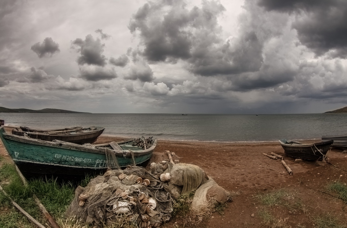 Старое море. Старая лодка на берегу. Рыбацкая деревня на берегу. Рыбацкая деревня у моря. Рыбачьи сети на берегу моря.